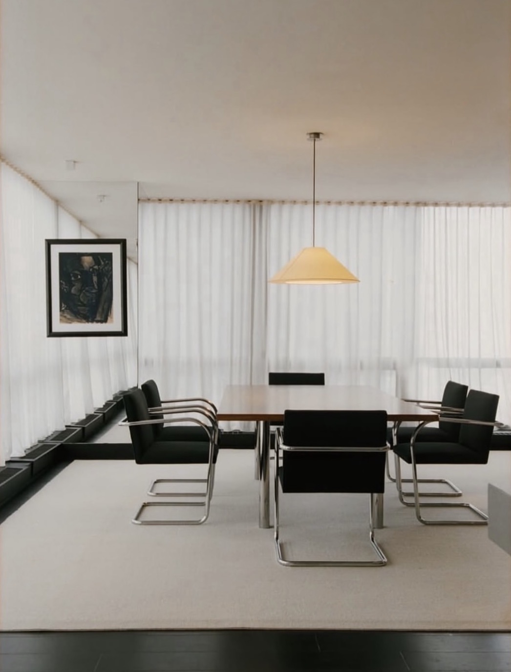 Salle de réunion avec fauteuils noirs, longue table et œuvre encadrée
